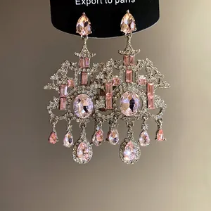 Dettaglio macro di orecchini stile palazzo vintage con cristalli rosa e trasparenti