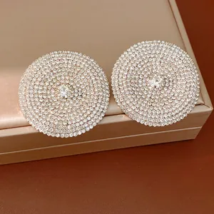 Primer plano de pendientes redondos plateados de gran tamaño con micro-pavé de strass
