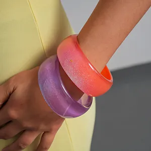 Close-up view of vibrant gradient resin geometric bangles featuring sparkling glitter detail