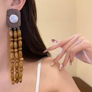 Vintage style wooden tassel earrings with pearl detail shown on an Asian model's ear