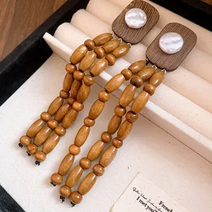 Close-up view of vintage style wood and pearl tassel earrings in a cream jewelry box