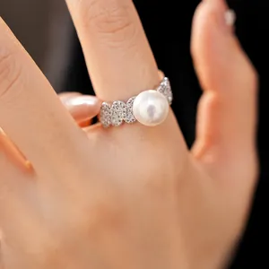 Macro detail of a shimmering pearl ring with sparkling zircons on a delicate finger.