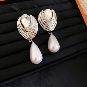 Elegant French teardrop pearl earrings with rhinestones on black velvet display