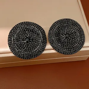 Primer plano de los pendientes redondos grandes adornados con brillantes cristales.