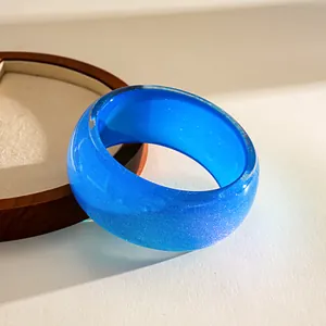 Close-up of a vibrant blue glitter resin chunky bangle with a smooth geometric design