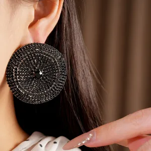 Detalle de primer plano de un pendiente circular de pedrería negra de gran tamaño en la oreja