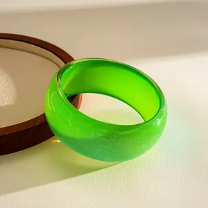 Detailed view of a vibrant green resin bangle with a sparkling glittery finish and smooth surface