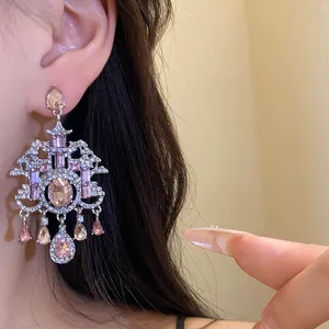 Dettaglio ravvicinato di orecchini a lampadario vintage con strass rosa indossati da una modella