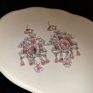 Vista macro dettagliata di orecchini a pendente con strass rosa in stile palazzo retrò