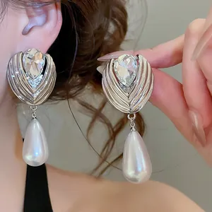 Close-up of elegant French style teardrop pearl earrings with rhinestones on ear.