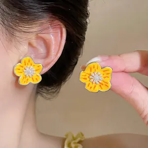 Detailed shot of yellow floral enamel stud earrings with zircon and pearl accents