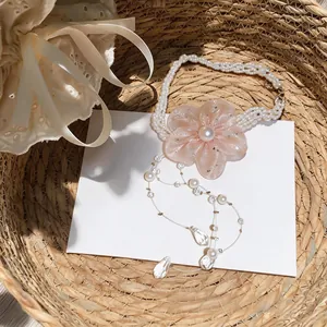 Detailed macro view of a pink chiffon flower necklace featuring pearl strands and crystal drops