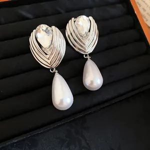 Close-up of French-style silver earrings with faceted crystal and teardrop pearls