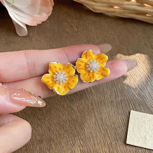 Detailed view of sweet yellow enamel flower stud earrings with pearl and zircon center