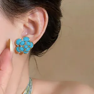 Close-up view of elegant vintage French style resin flower stud earrings worn on model