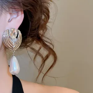 Close-up of French style rhinestone waterdrop pearl earrings on ear for elegant look