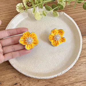 Detailed view of yellow enamel flower stud earrings with sparkling zircon centers