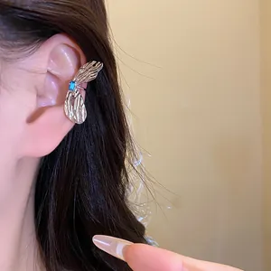 Detailansicht eines silbernen Schmetterlings-Ohrklemms mit blauem Zirkonia-Stein