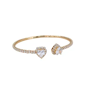 Elegant gold open cuff bracelet featuring twin crystal hearts and pavé set stones