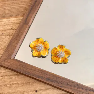 Close-up of vibrant yellow enamel flower earrings with sparkling cubic zirconia center