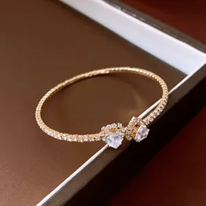Close-up detail of a gold open heart bracelet featuring clear gemstones and pavé diamonds
