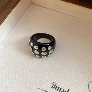 Detailed macro view of a chunky black resin ring with metallic silver studs on a tray