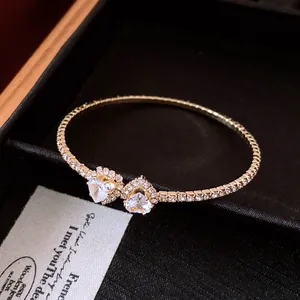 Close-up of heart-shaped crystal open bangle with diamond accents in black gift box.