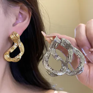 Primer plano de pendientes geométricos de metal texturizado en acabado dorado y plateado
