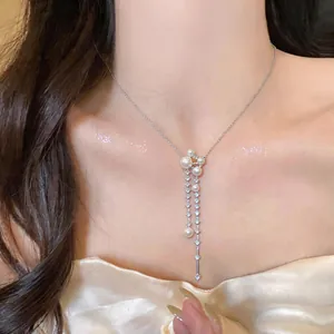 Close-up detail of an elegant French style pearl and zircon tassel necklace on model