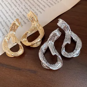 Vista detallada de pendientes de aro geométricos texturizados bañados en oro de 18k