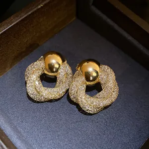 Close-up of vintage-style gold earrings with mesh twisted flower design and crystal details