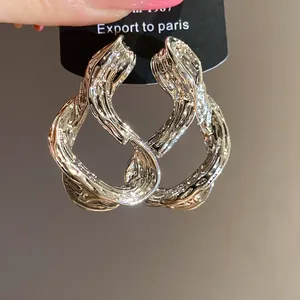 Primer plano de pendientes geométricos retorcidos bañados en plata con textura de corteza.