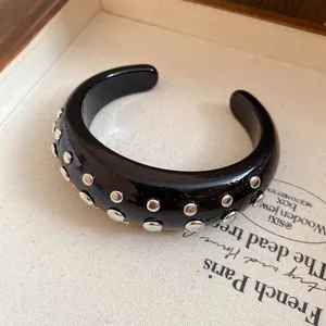 Close-up of black resin open cuff bracelet with silver-tone stud details