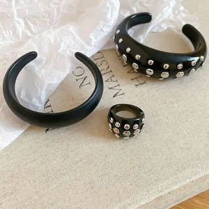 Detail of black resin cuff bracelet and matching ring set with silver studs