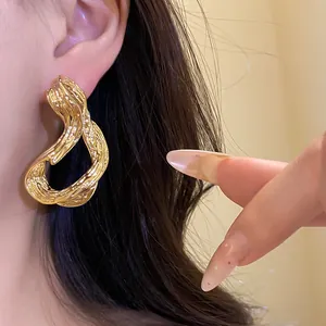 Primer plano de la textura fundida de pendientes de aro irregulares bañados en oro de 18k