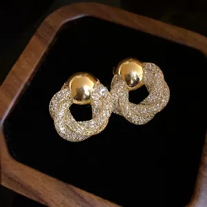 Close-up view of elegant vintage gold mesh twisted hoop earrings on black velvet.