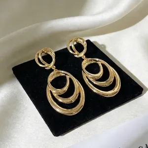 Macro shot of gold layered oval hoop dangle earrings on black velvet background.
