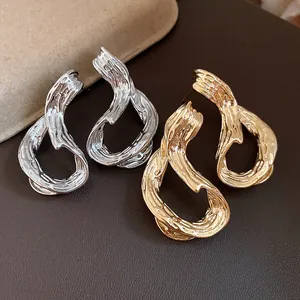 Detalle de pendientes geométricos con relieve bañados en oro de 18k y plata.