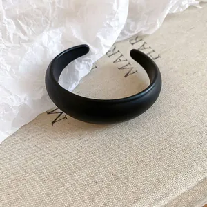 Close-up of minimalist black matte resin oval open bangle with smooth texture