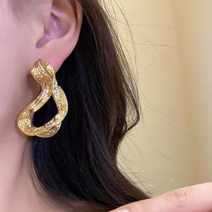 Primer plano de elegantes pendientes de aro geométricos bañados en oro de 18k