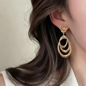Close-up of elegant gold triple nested oval hoop drop earrings on model