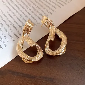 Primer plano de pendientes geométricos bañados en oro de 18k con acabado de textura