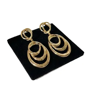 Elegant gold-tone metallic multi-layer oval drop earrings displayed on black velvet