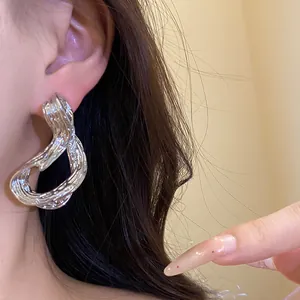Detalle de cerca de un pendiente geométrico de plata texturizada en la oreja de mujer