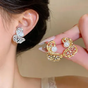 Vista dettagliata di orecchini placcati oro e argento con design traforato e perle