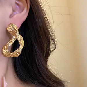 Primer plano de elegantes pendientes geométricos bañados en oro de 18 quilates