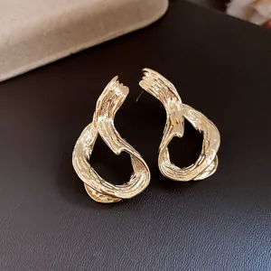Vista detallada de pendientes geométricos bañados en oro de 18k con acabado rugoso.