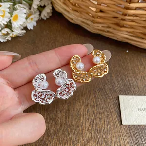 Dettaglio di orecchini traforati placcati oro 18K con zirconi e perle su argento.