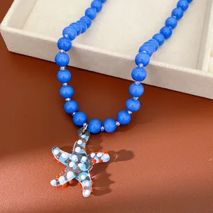 Close-up detail of a blue beaded necklace with a glass starfish pendant on brown leather