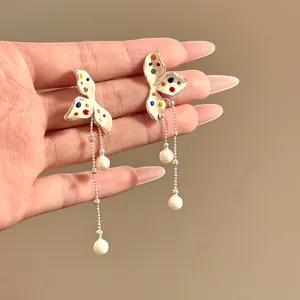 Detail view of elegant colorful polka dot flower tassel earrings with white pearls.
